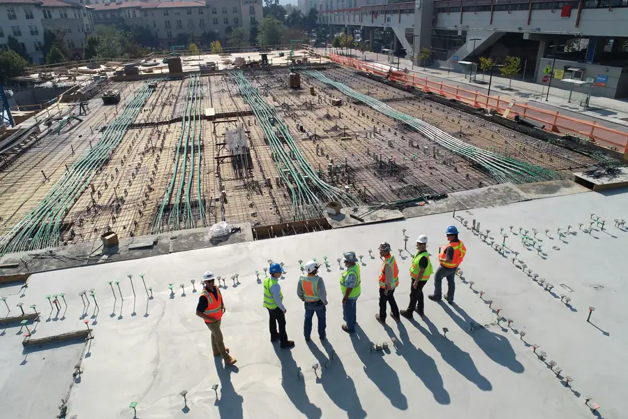 Équipe de chantier en gilets et casques sur une dalle béton, devant un plancher ferraillé